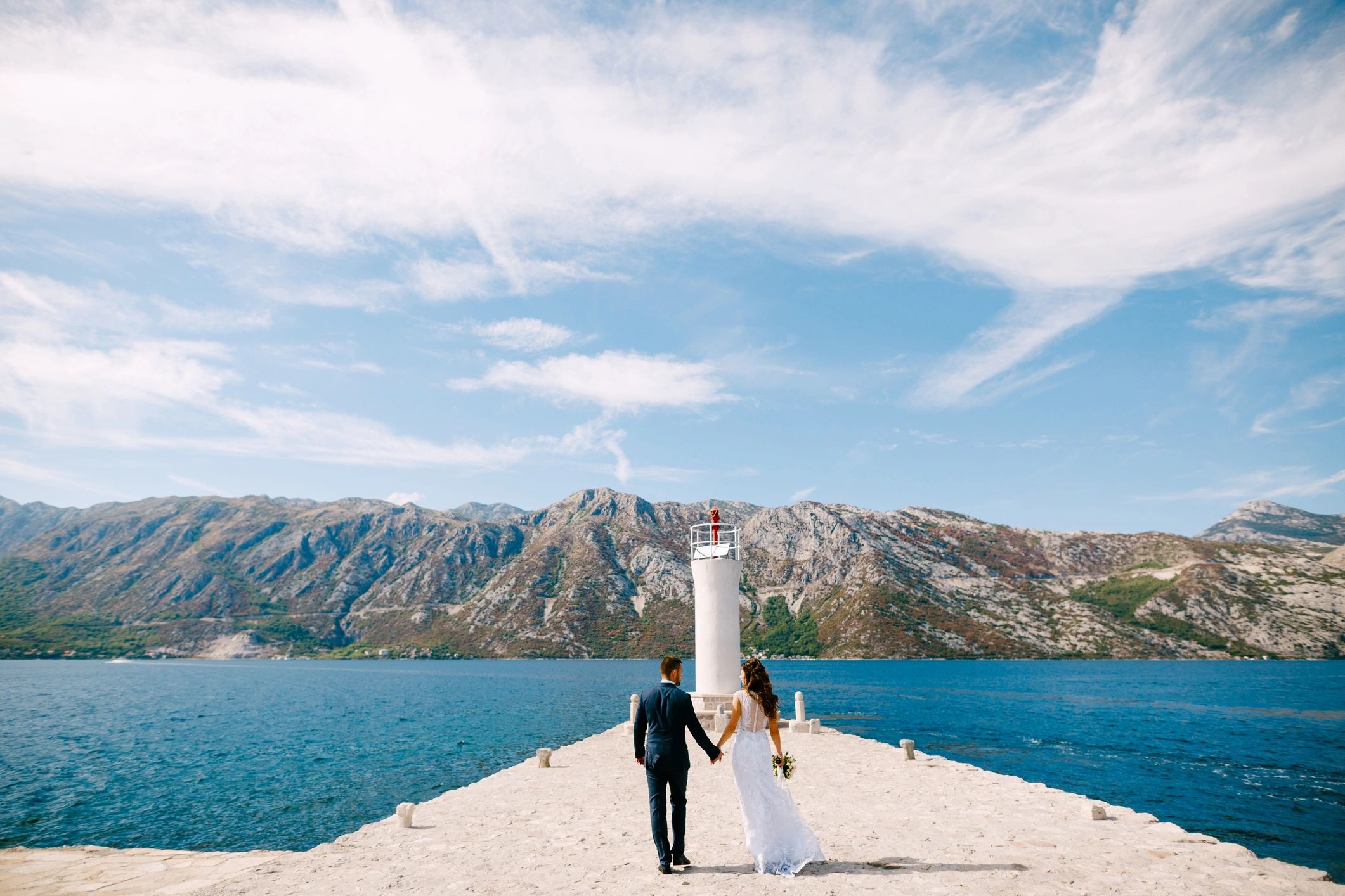 Bride and groom walking on a sunny pier