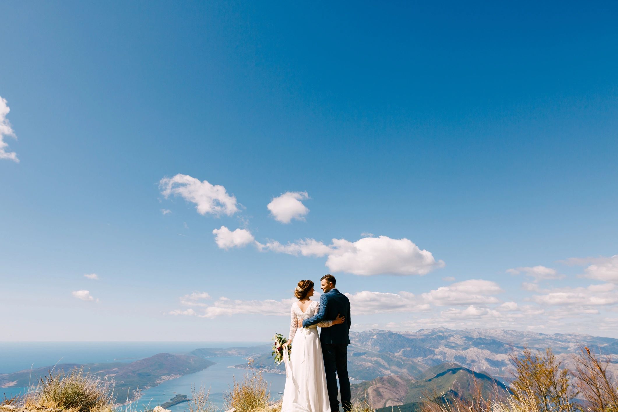Newlyweds embracing with scenic mountain backdrop